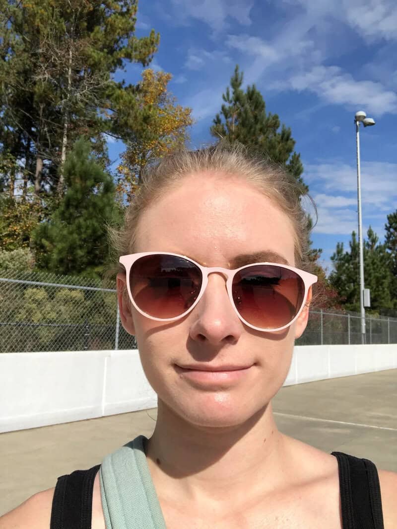 Close-up of a woman with sunglasses outdoors on a sunny day.