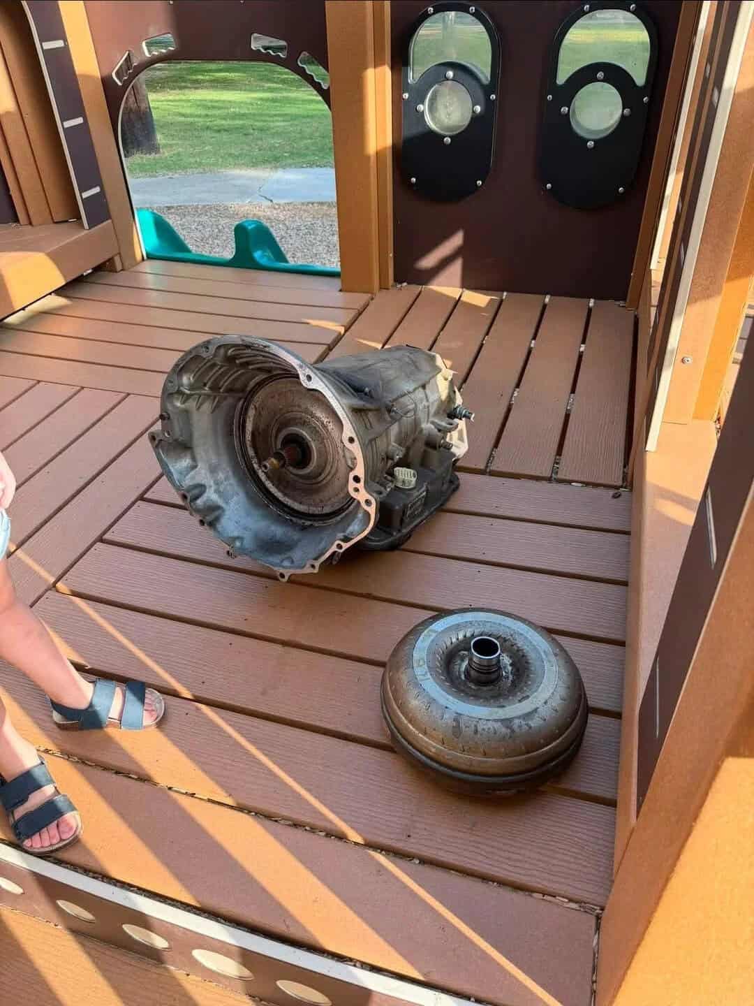 Playground with a car transmission and a tire on the wooden floor.