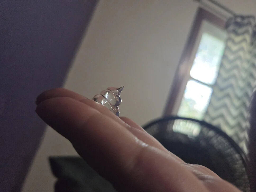 Small glass unicorn figurine on a person's finger.