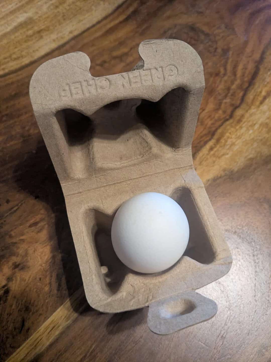 Egg in a cardboard carton with a wooden surface background.