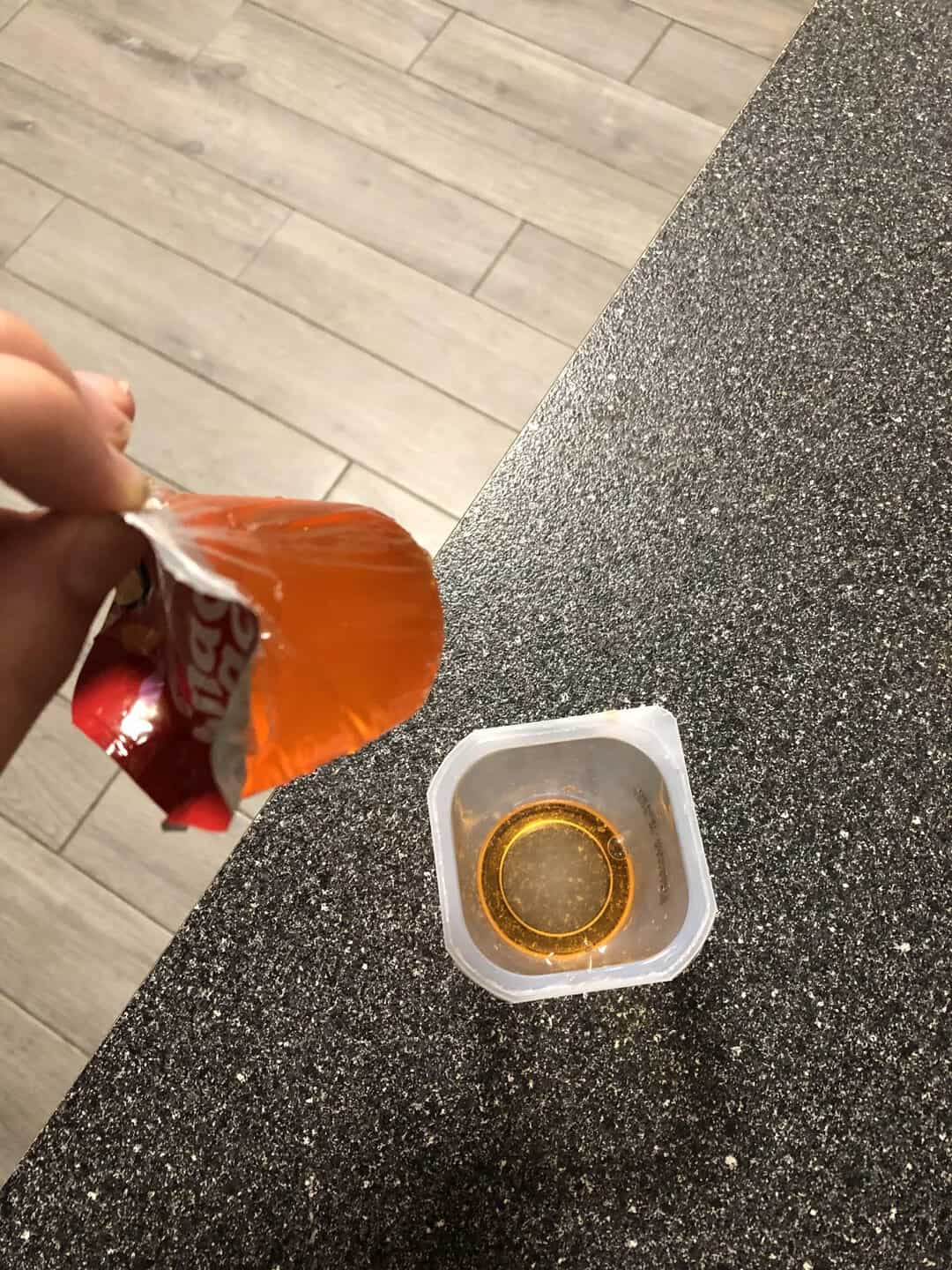 Person opening a snack package over a container with a gold ring inside.