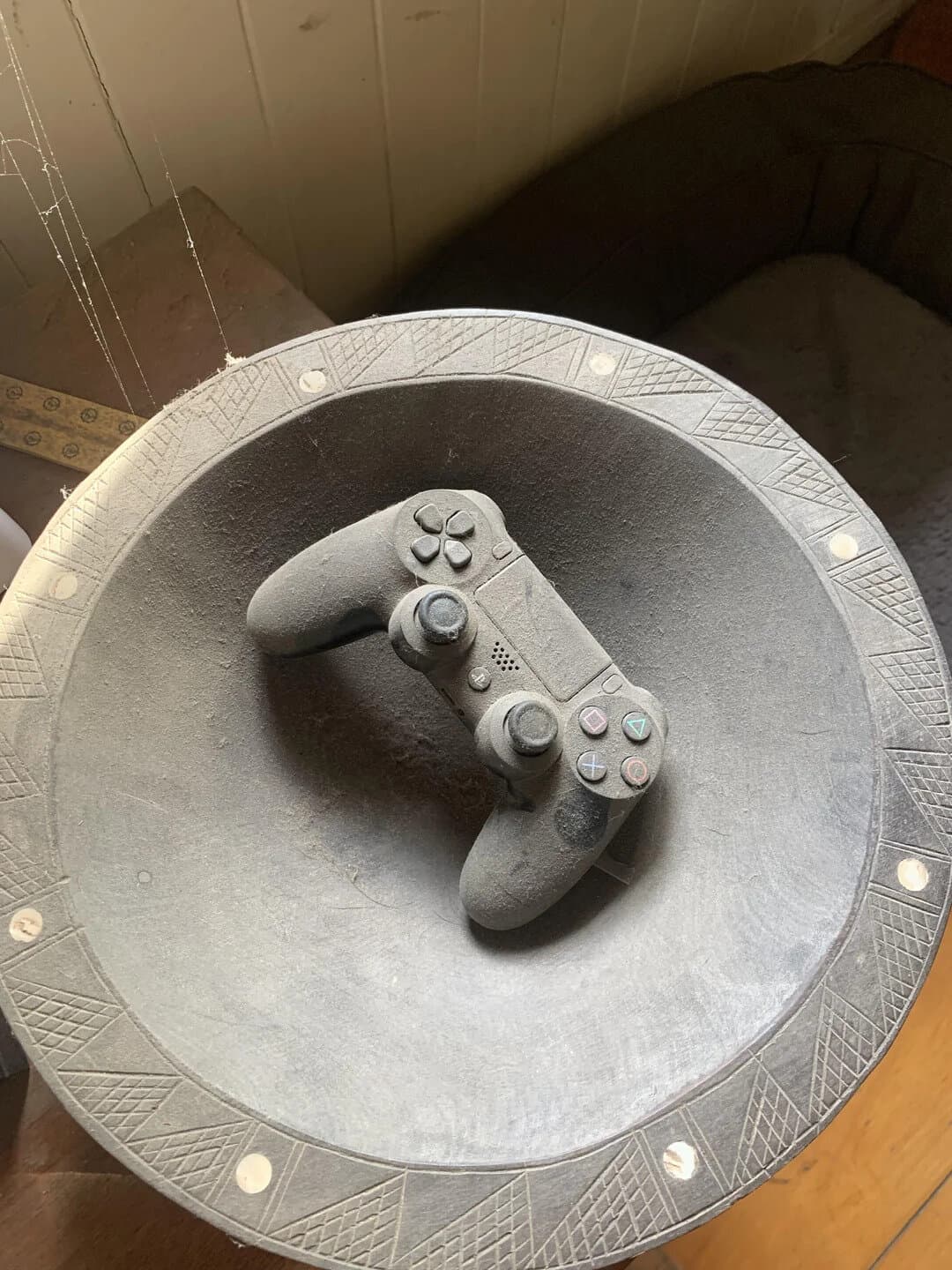 PlayStation controller on a round table with a patterned edge.