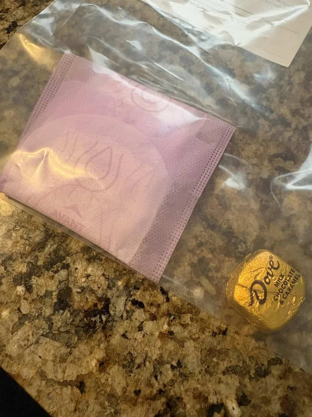 Pink face mask and Dove chocolate on a granite countertop.