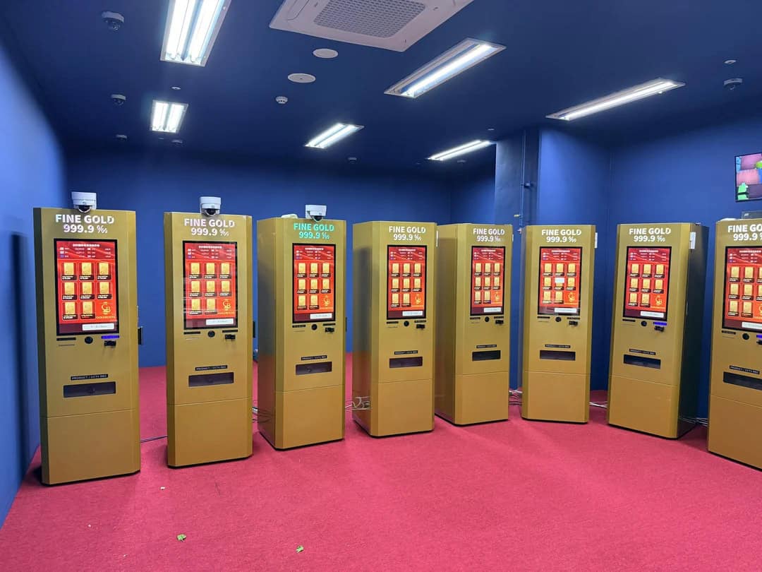 Row of gold vending machines with a pink carpet and blue walls.
