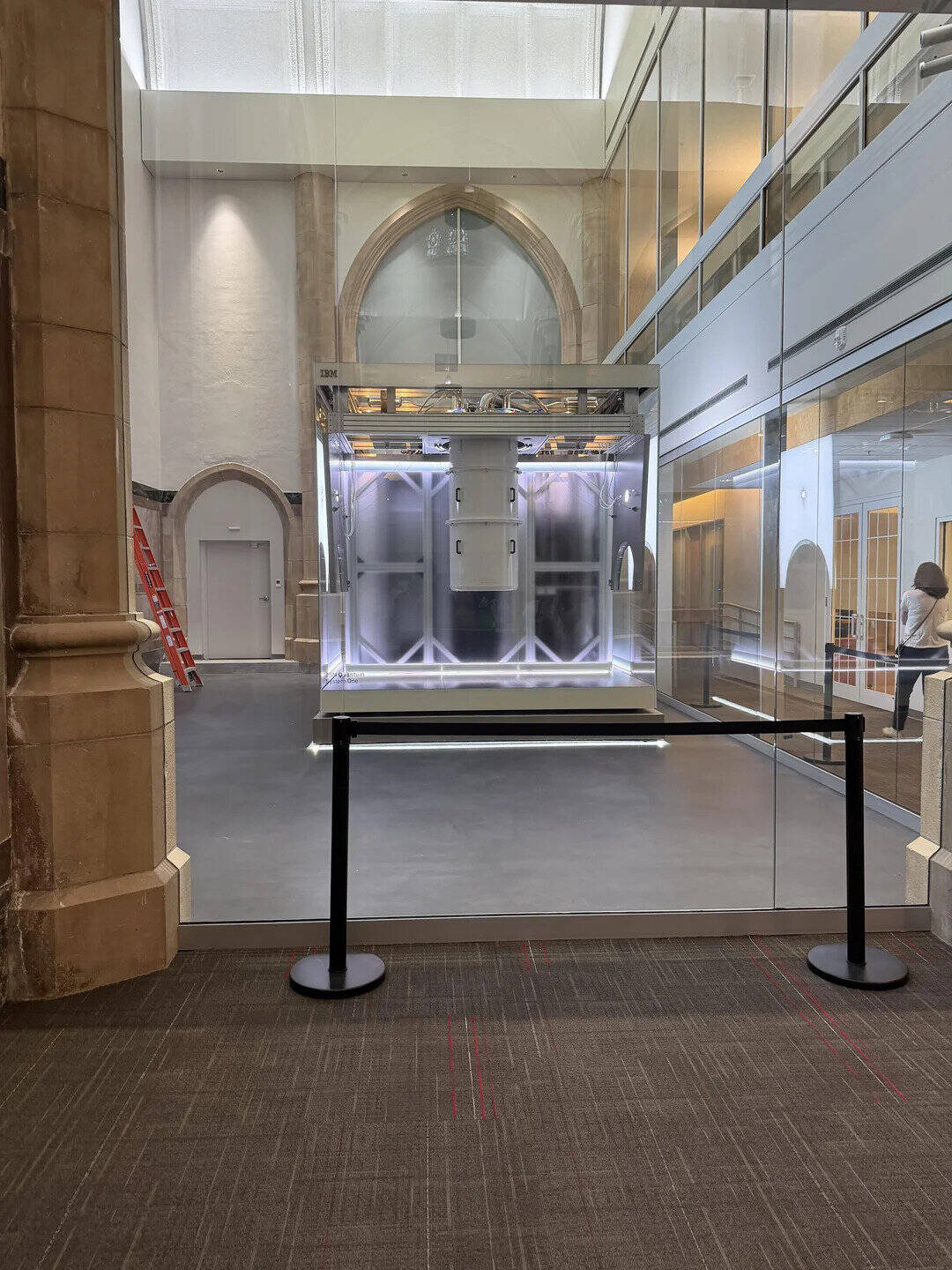 Elevator inside a building with glass walls and a barrier in front.