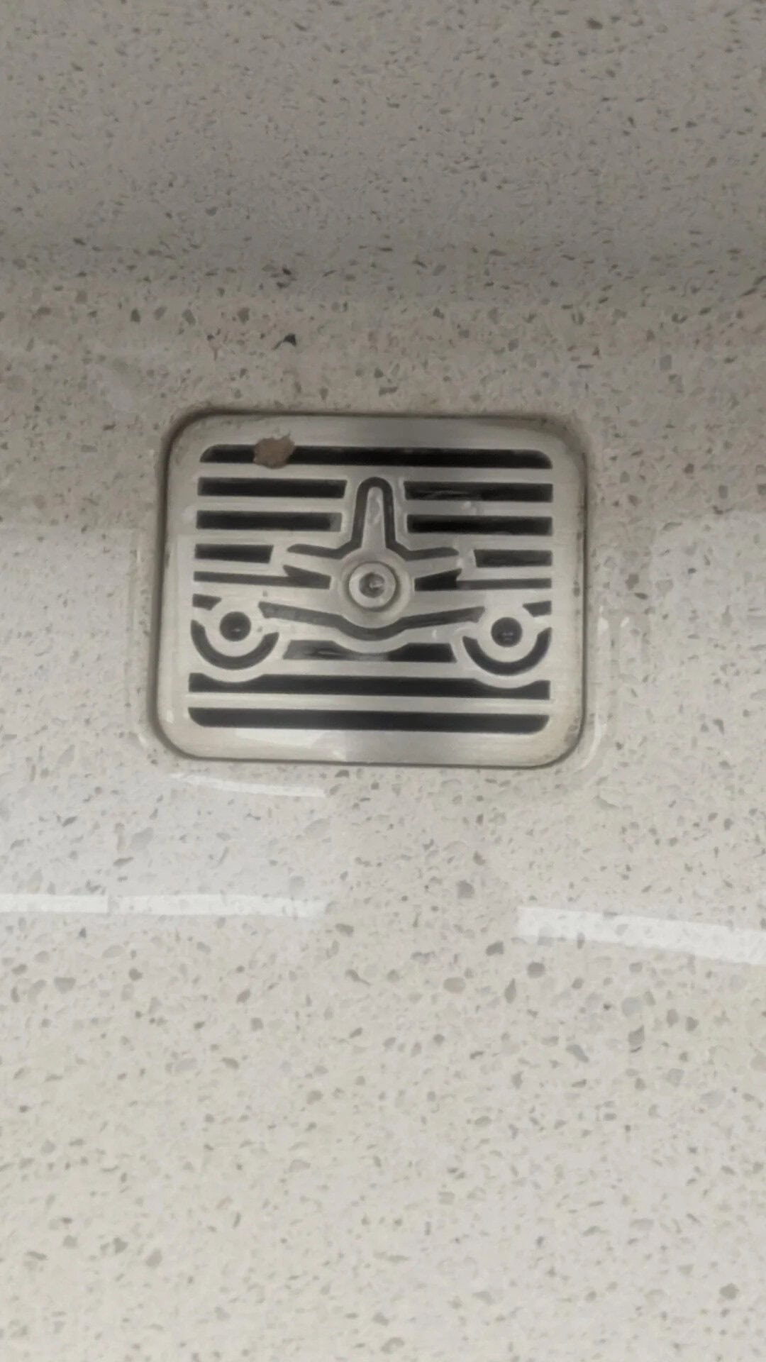 Drain cover with a maze-like pattern on a ceiling.