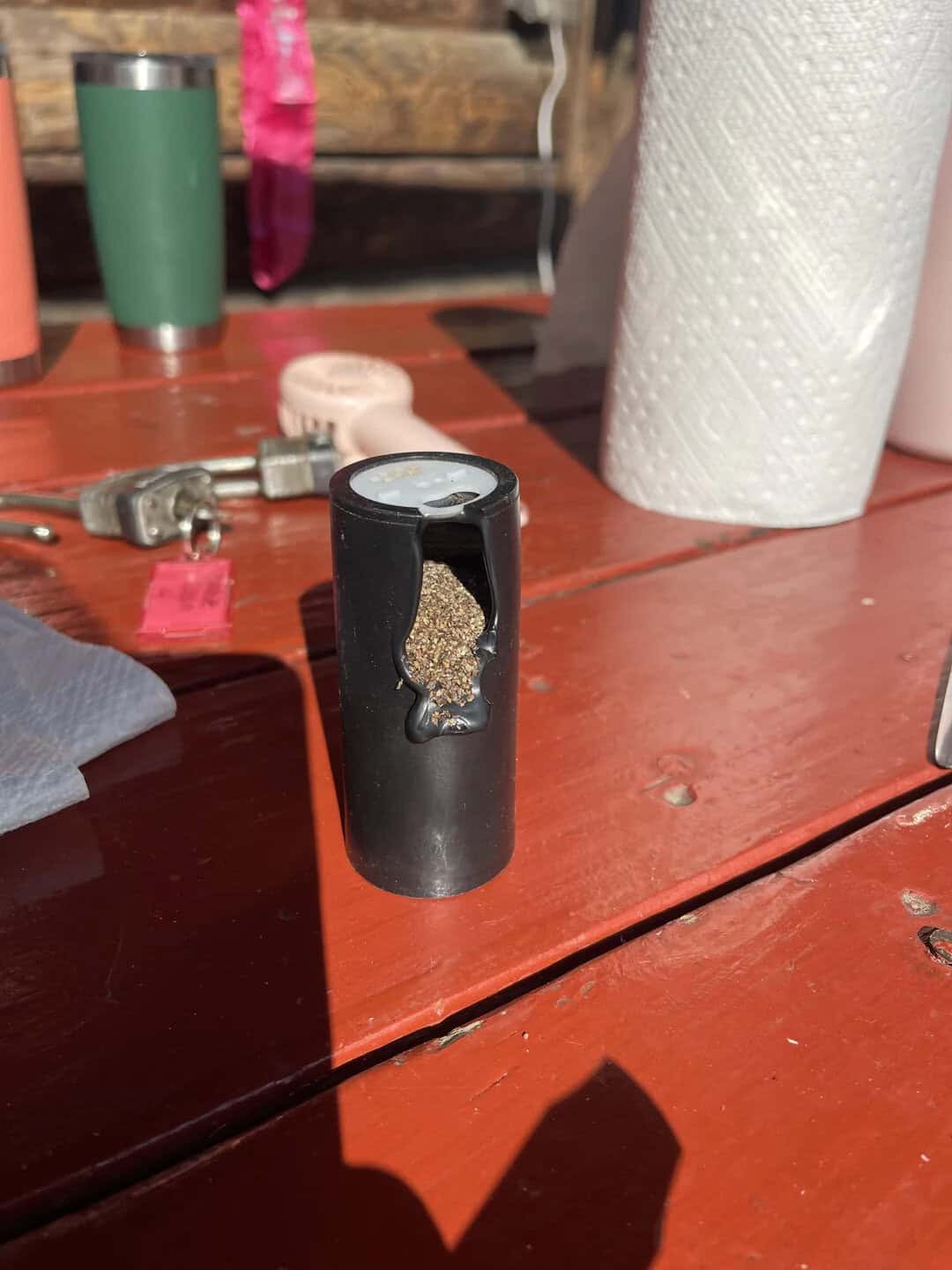 A black container with a cannabis bud inside on a wooden table.