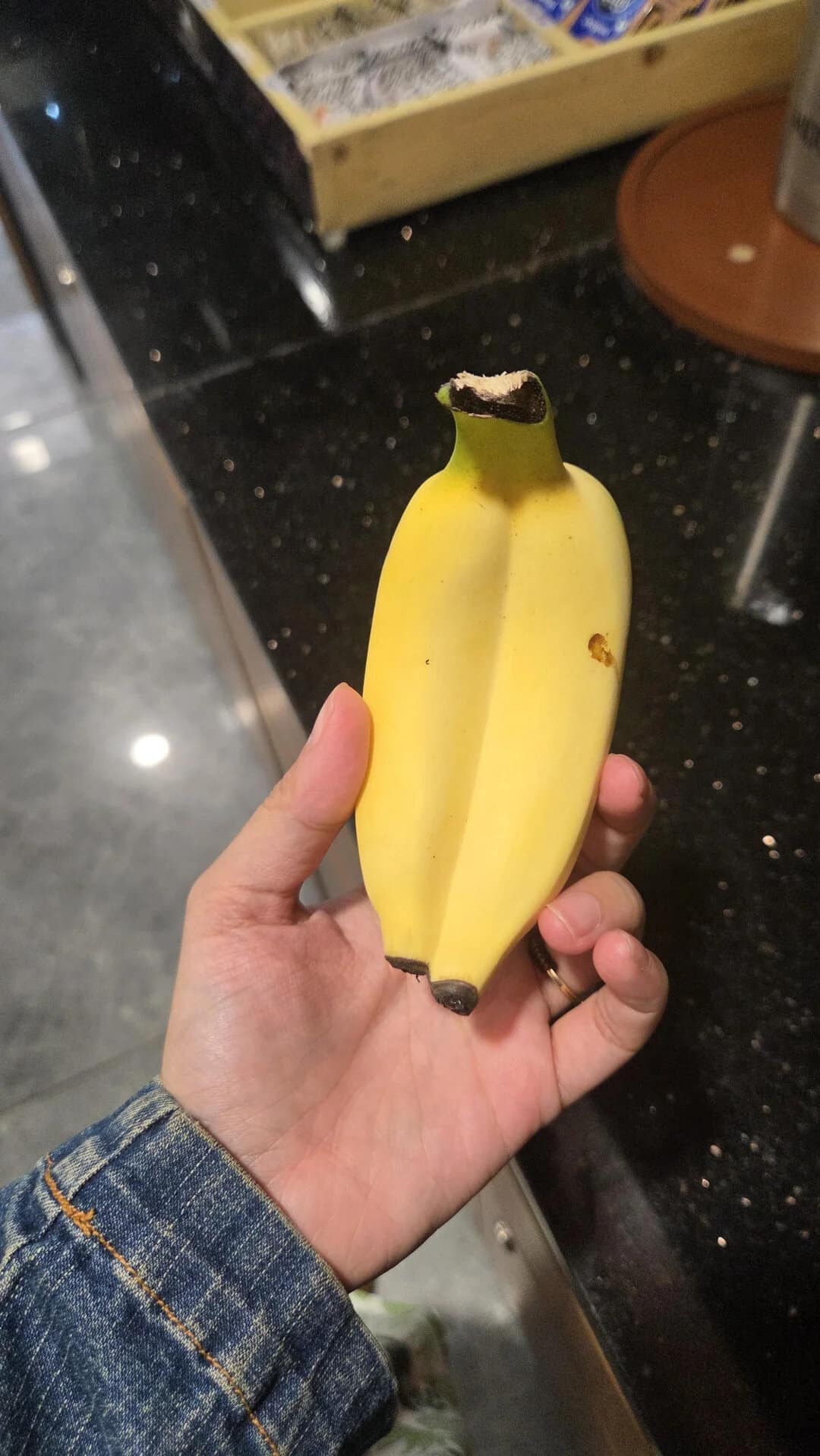 A hand holding a banana with a dark spot on the top.