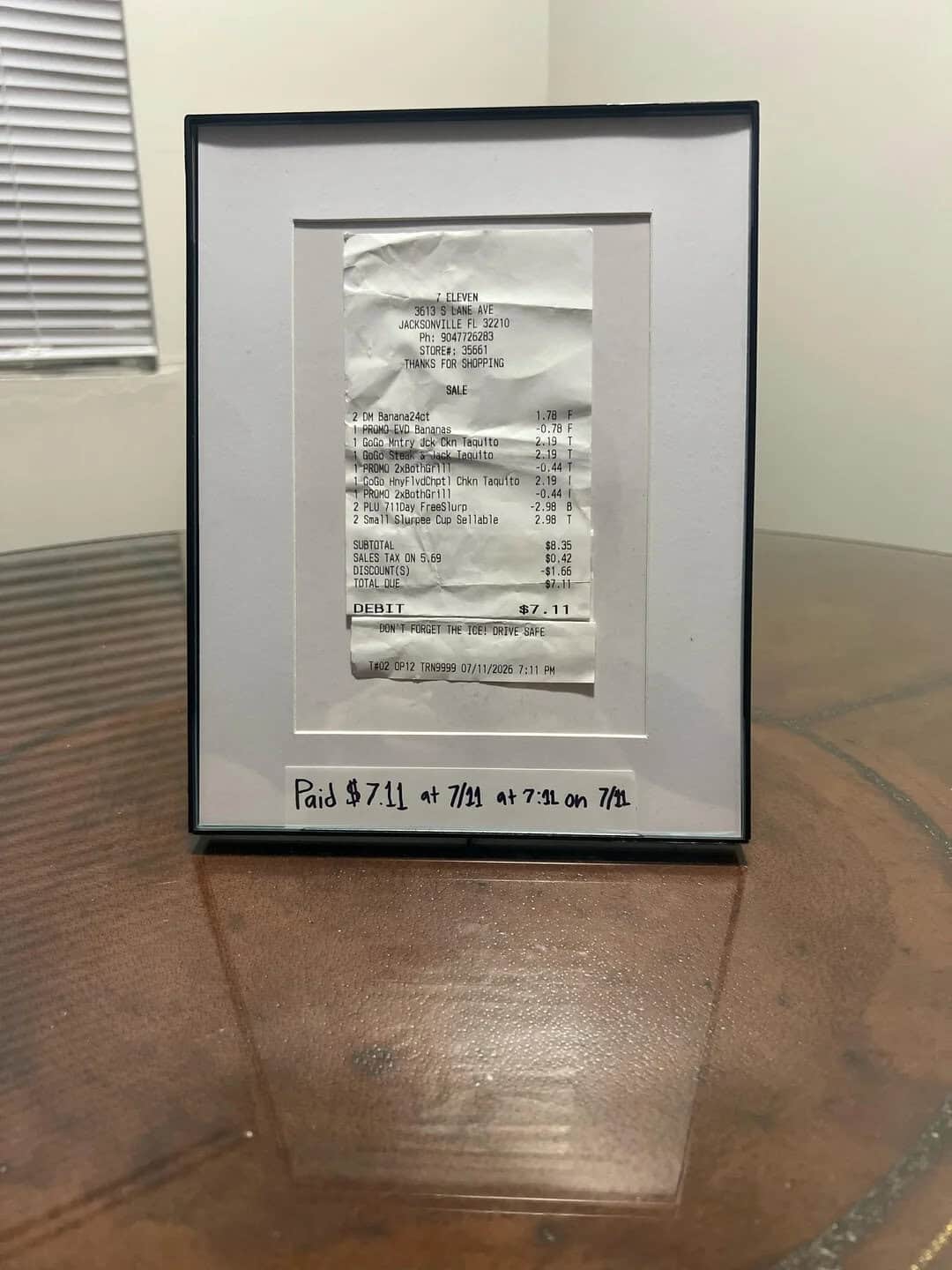 Framed receipt with handwritten note at the bottom reading 'Paid $7.11 #714 at 7:30 am 7/2'.