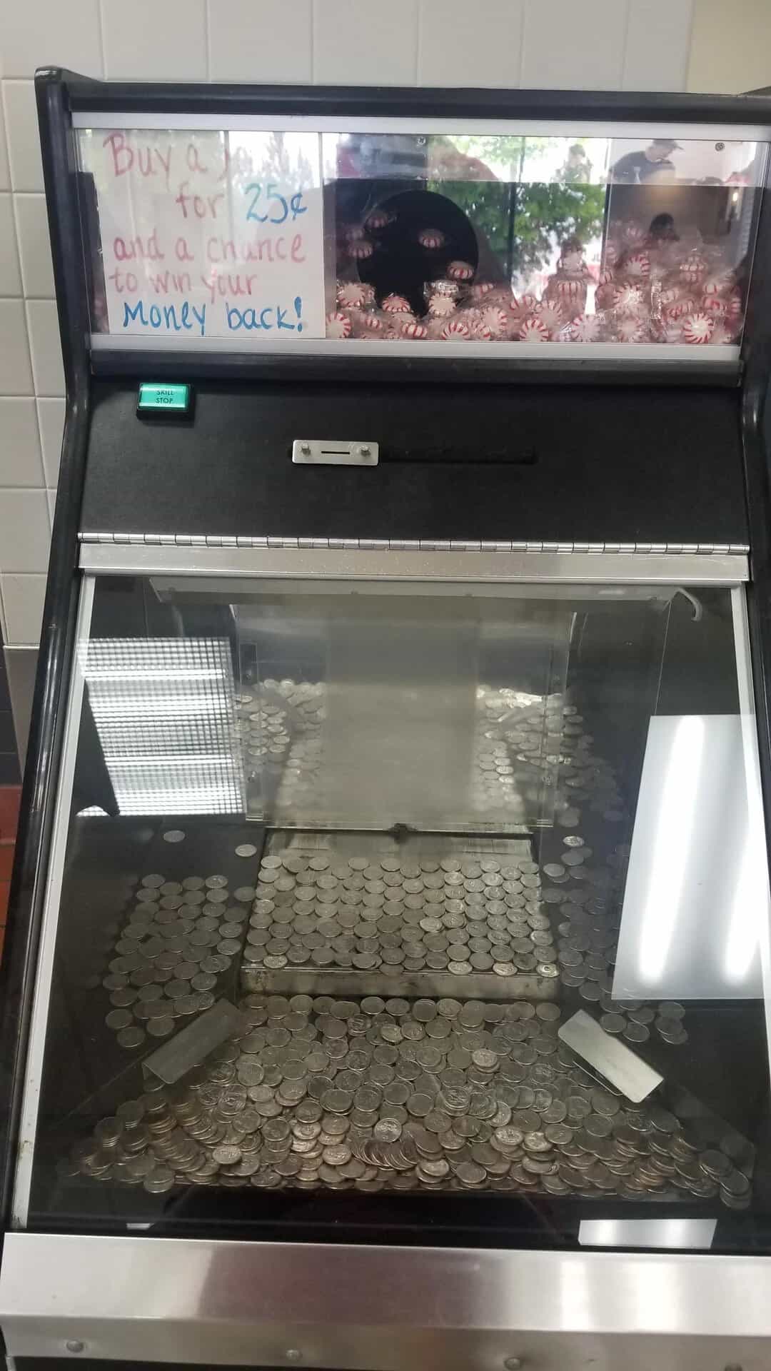 Coin collection in a glass display case with a sign about buying coins for 25 cents.