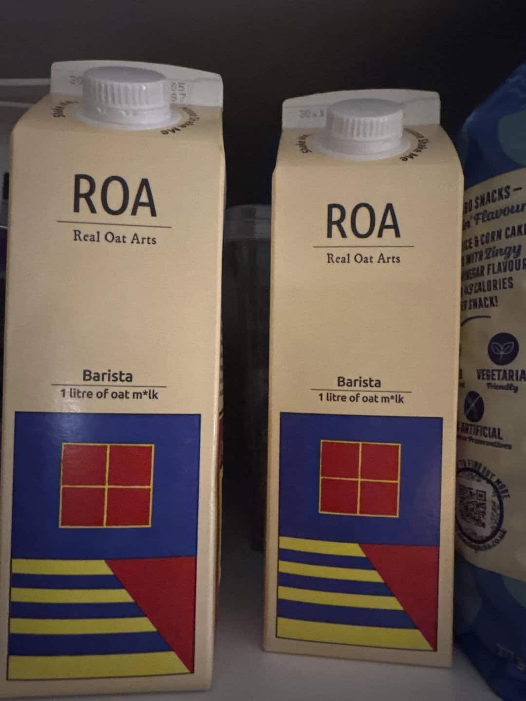 Two cartons of ROA Real Oat Arts oat milk with a red, yellow, and blue geometric design.