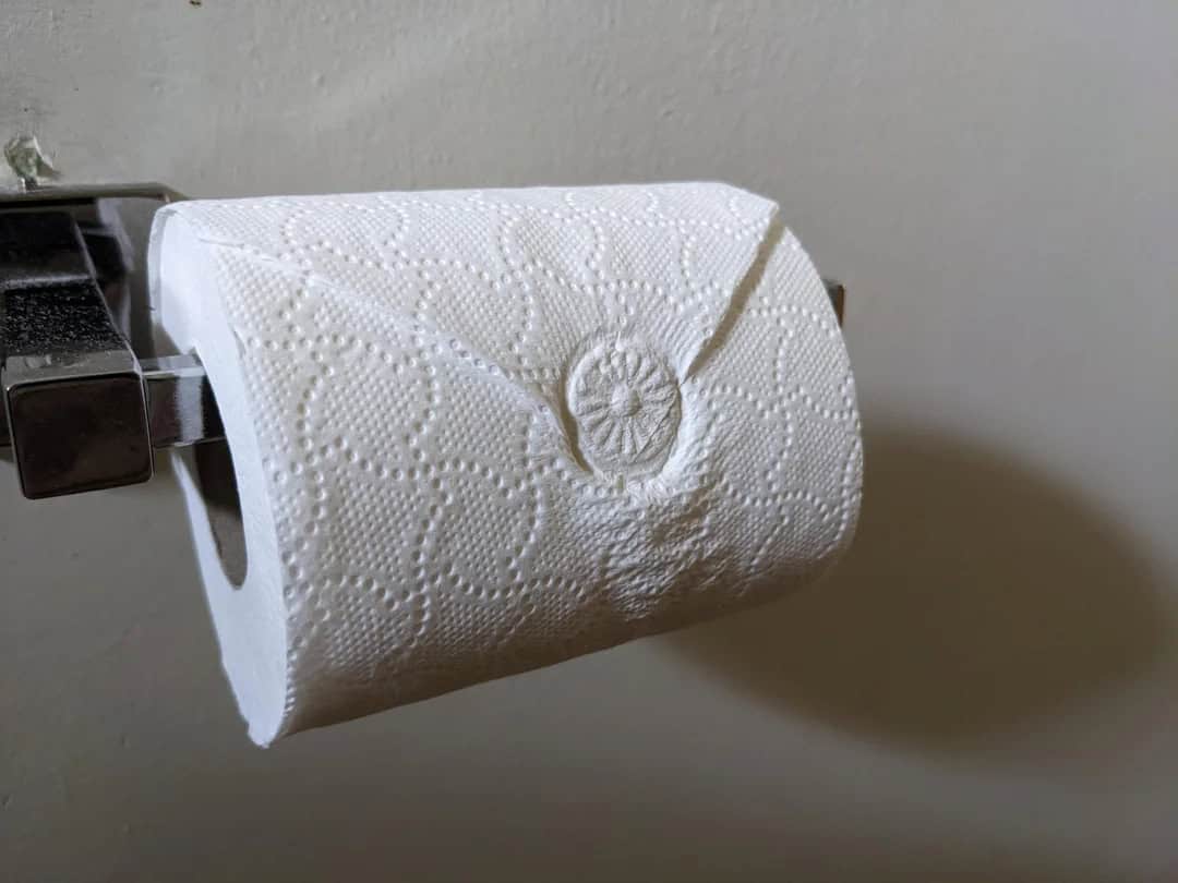 Toilet paper roll with a needle and thread sewing a button on it.