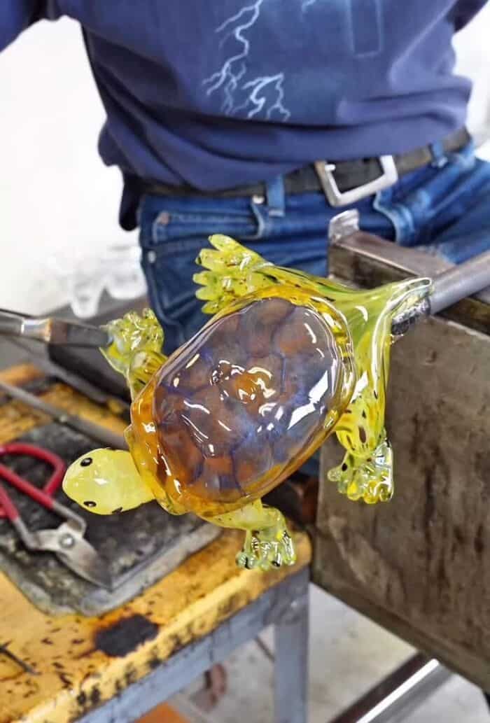 Molten glass sculpture of a turtle with a turtle shell and limbs in yellow and brown.