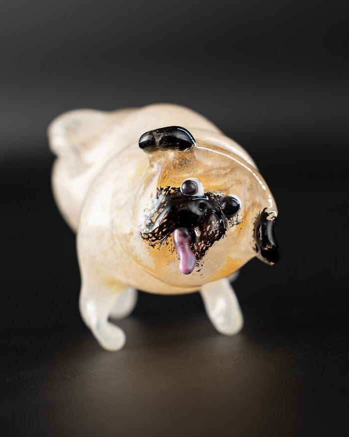 Glass sculpture of a dog with black ears, eyes, nose, and tongue sticking out.