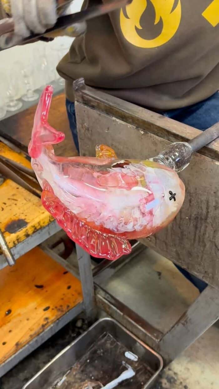 Glass sculpture of a pink and white fish with a black eye and fins.
