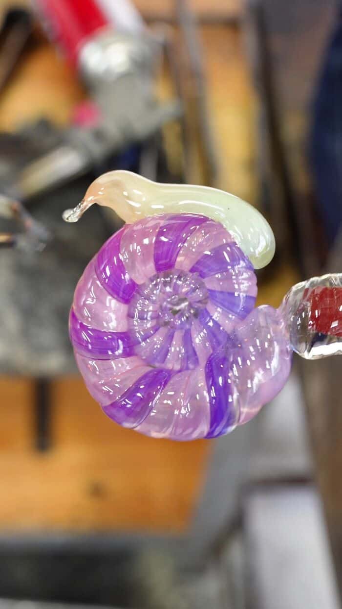 Colorful glass sculpture of a snail with purple and cream swirls.