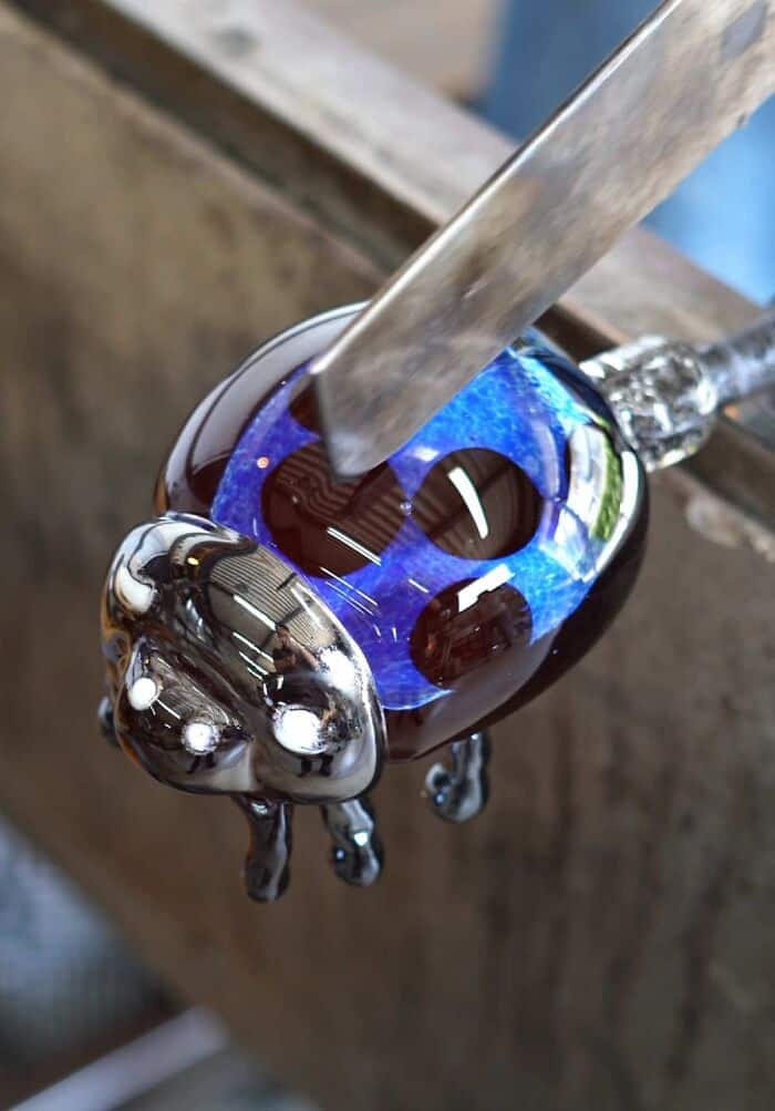 Molten glass being shaped with a metal tool by a Japanese artist.