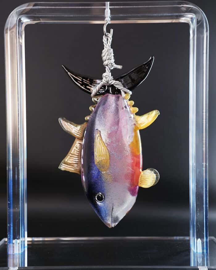 Colorful glass fish sculpture hanging in a display case.