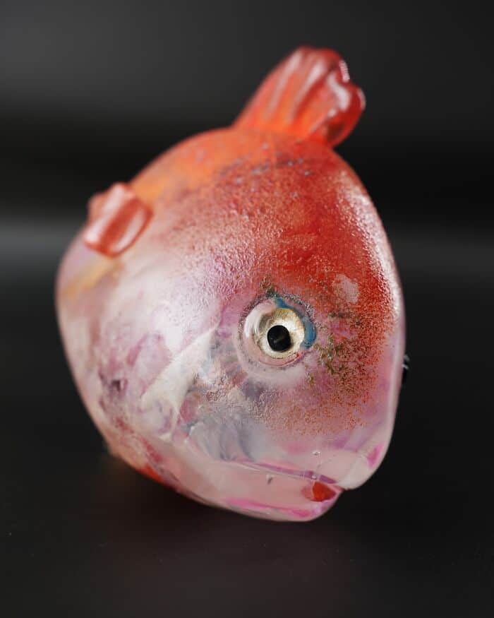 Colorful glass fish sculpture with detailed fins and eye, on a black background.