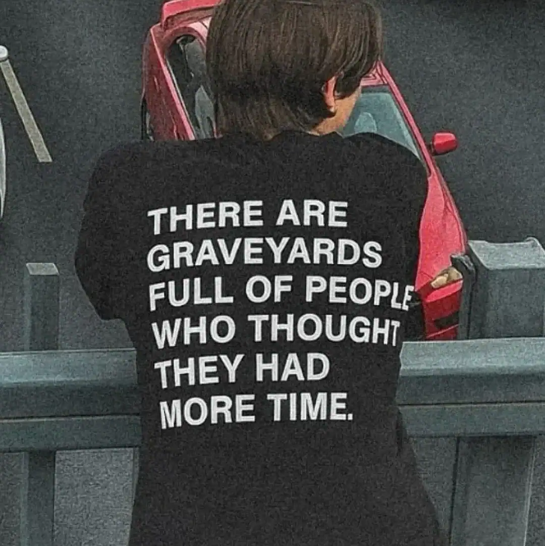 Person wearing a black hoodie with white text about graveyards and time.