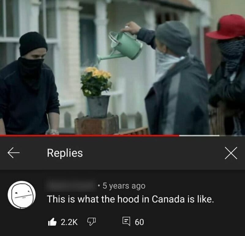 Three people with masks and hoodies watering a potted plant on a street.