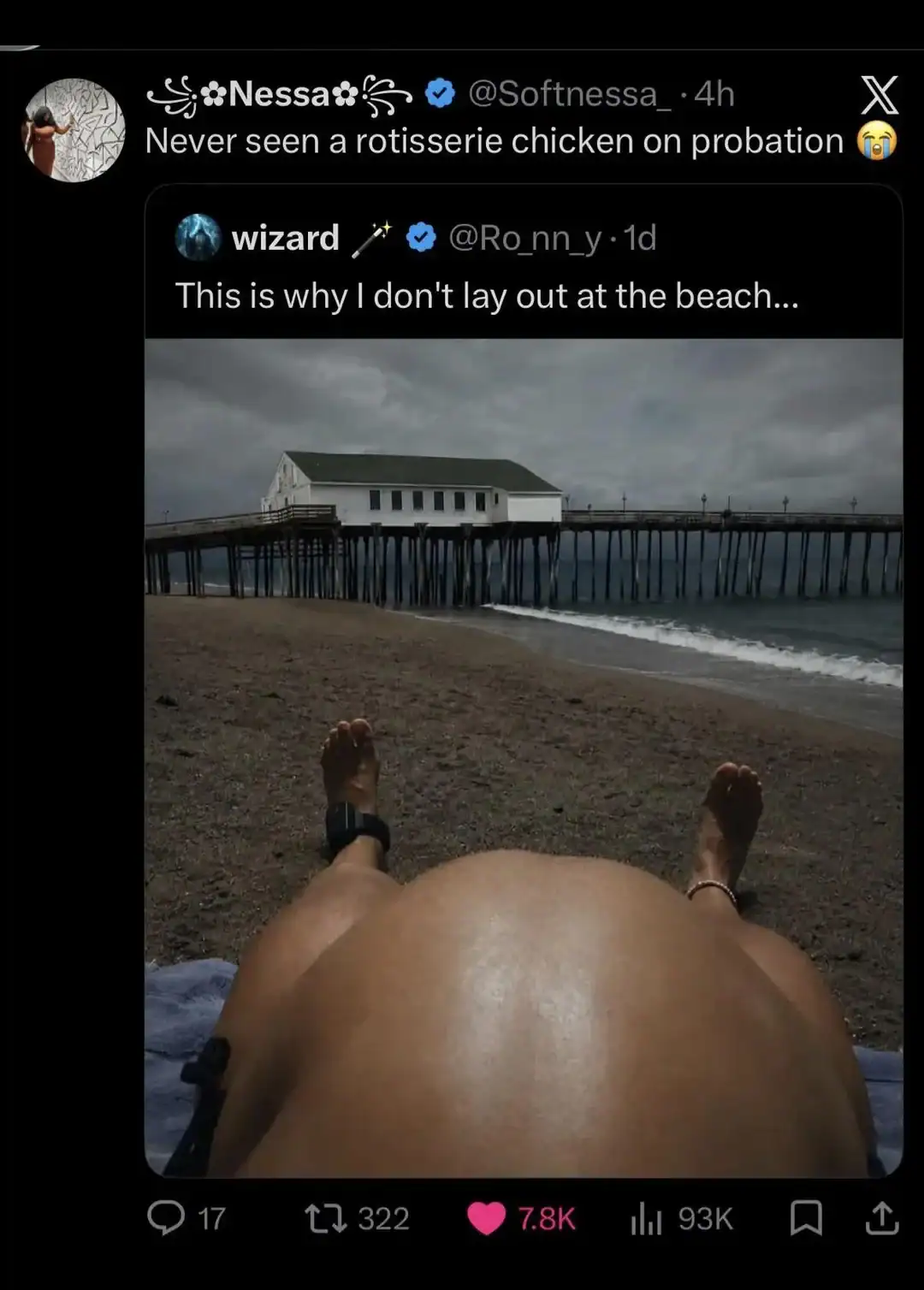 Person lying on beach with view of pier and building at the beach.