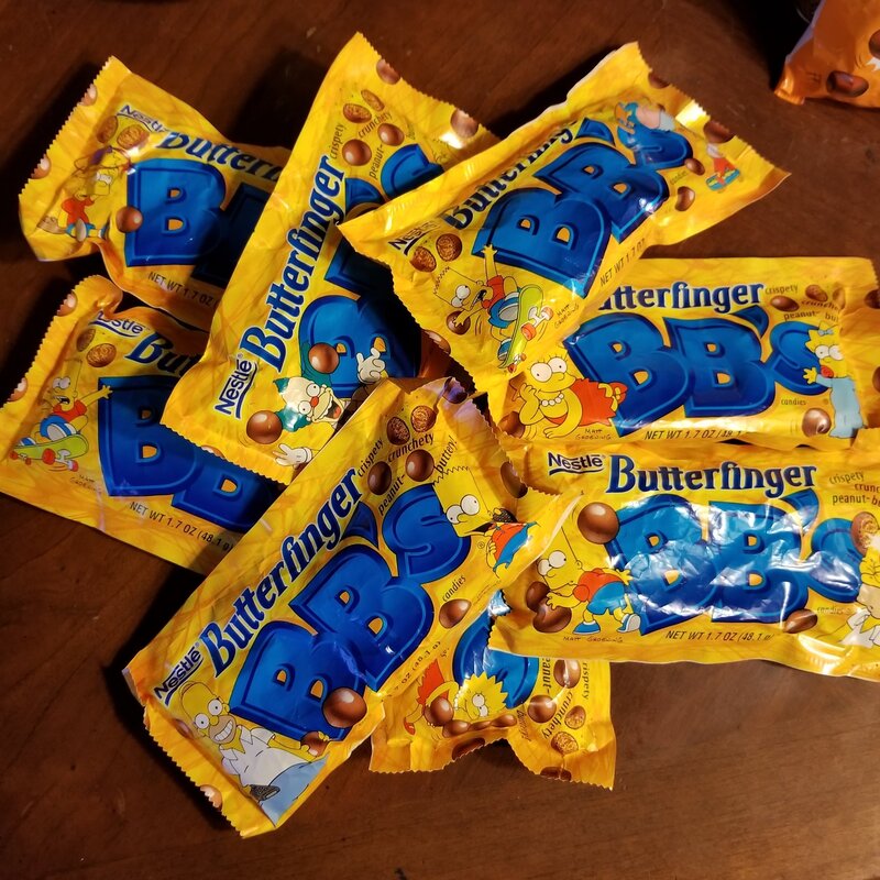 Multiple packages of Nestlé Butterfinger BBS candy on a wooden surface.