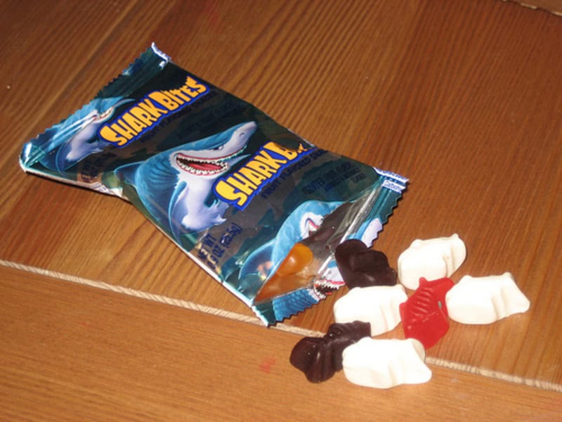 Shark Bites gummy candies with shark packaging on a wooden surface.
