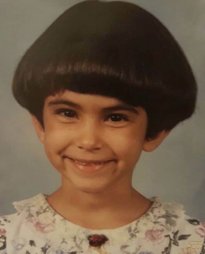 Child with a bowl haircut smiling in a school photo.