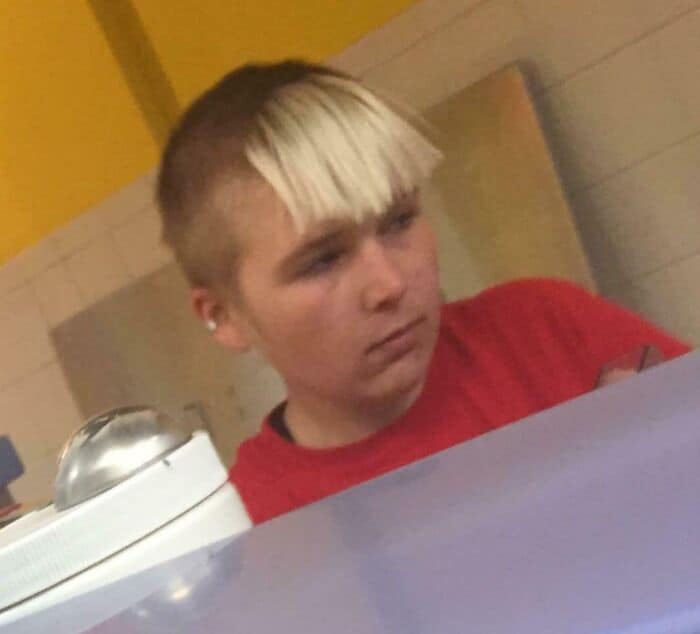 Teen with two-tone blonde and brown haircut, wearing a red shirt.