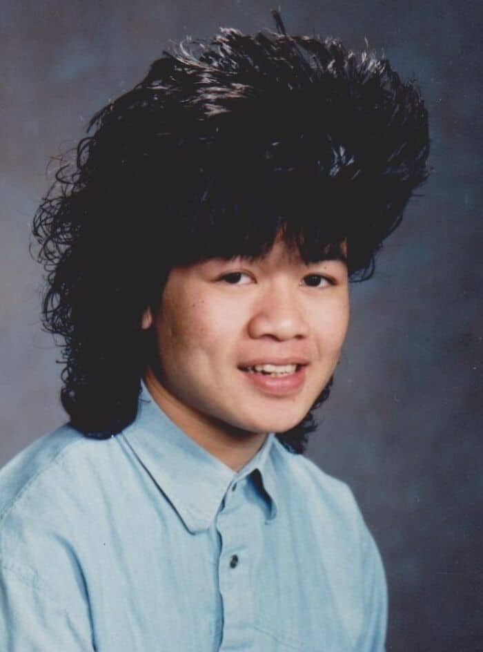 Young man with big, voluminous 80s hairstyle, wearing a light blue shirt.