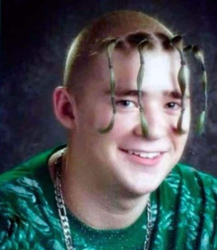 Young man with dreadlocks styled as hair, smiling, wearing a green shirt and chain.