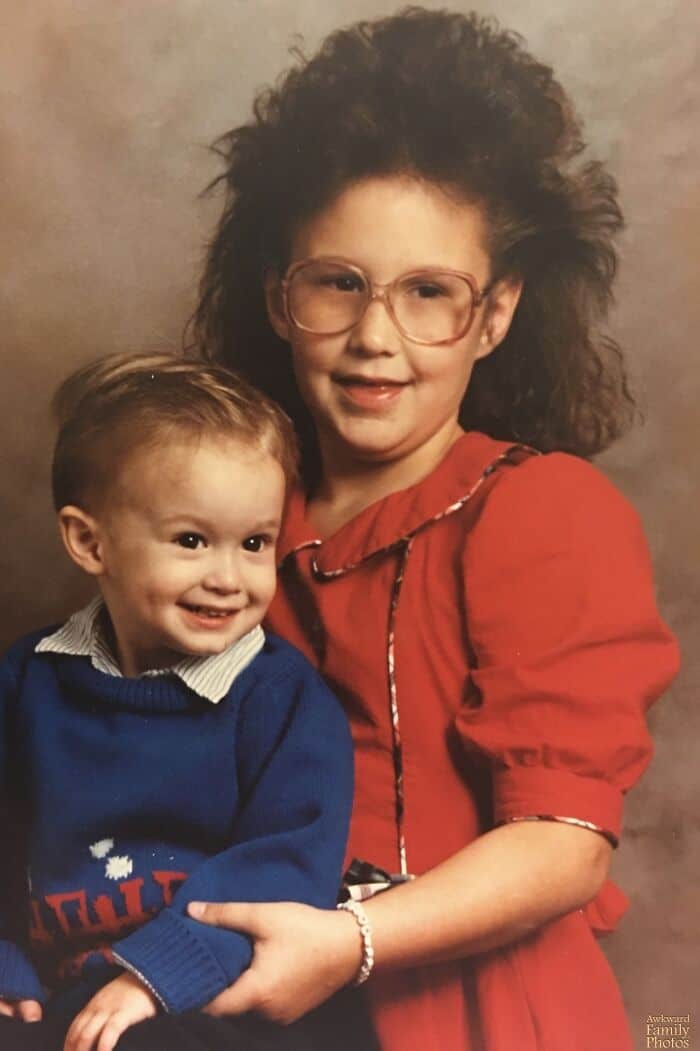Two children with big hair, glasses, and colorful clothes, one in red and one in blue.