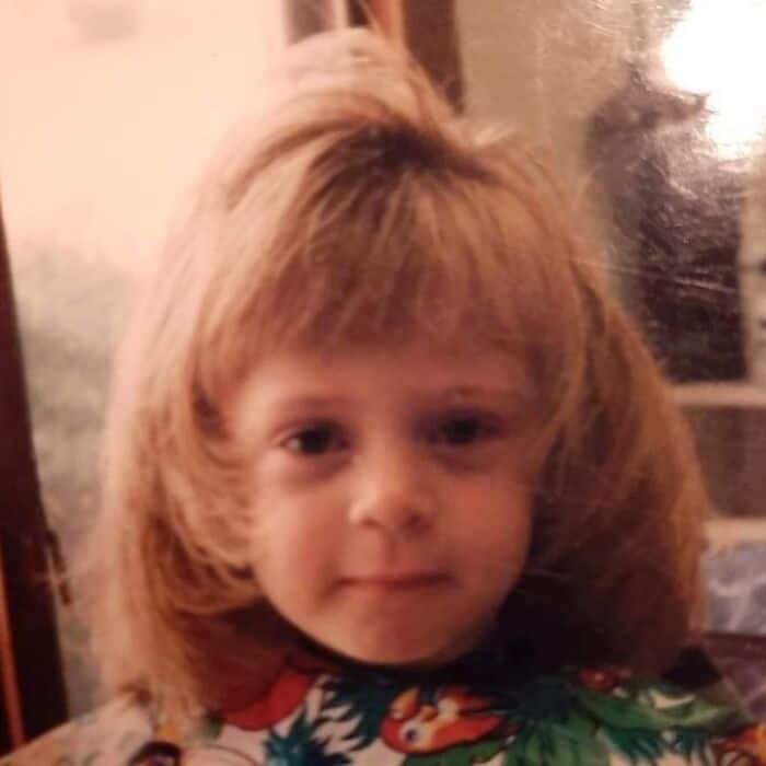 Child with big, voluminous 80s-style hair, wearing a colorful shirt.