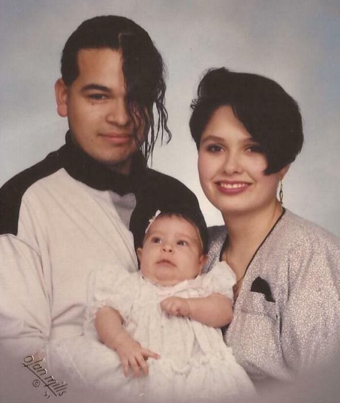 Family portrait with 80s/90s hairstyles, man with long curly hair, woman with short dark hair, baby.