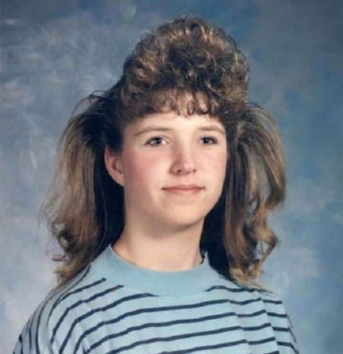 Girl with big, teased 80s hairstyle and striped shirt, smiling.