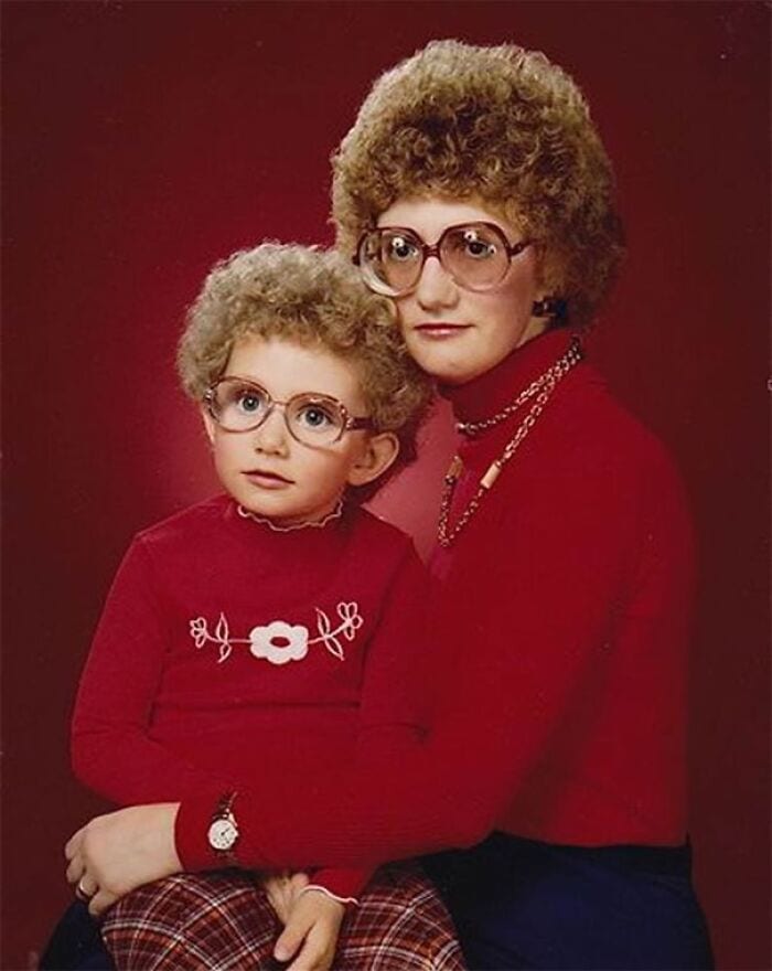 Mother and child with 80s hairstyles, glasses, red sweaters, and plaid pants.