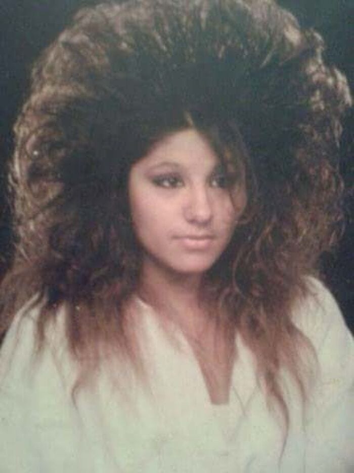 Woman with big, voluminous 80s/90s hairstyle and natural makeup.