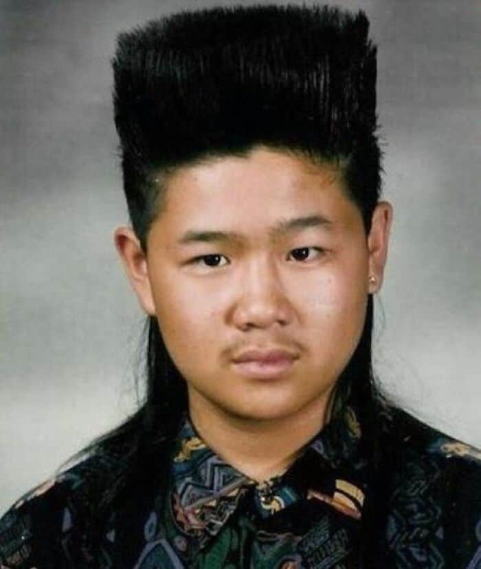 Young person with tall, flat-top hairstyle, wearing a patterned shirt.