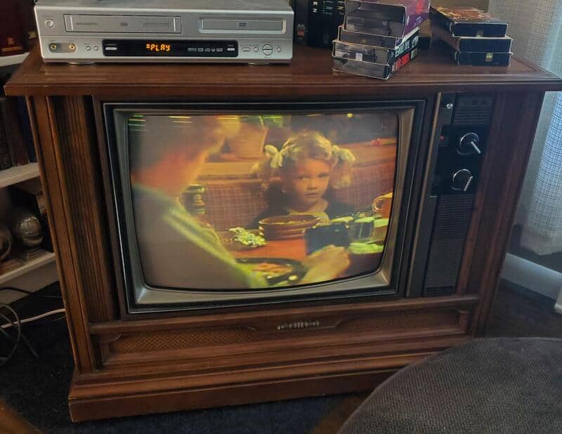 Vintage TV showing a young girl with pigtails at a family gathering.