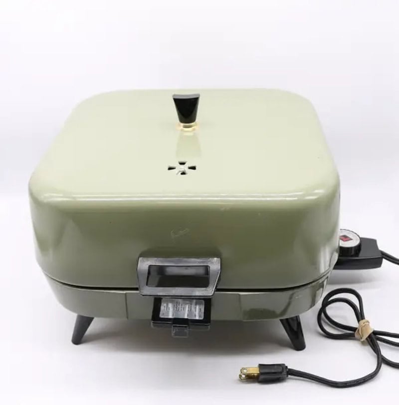 Vintage green sandwich maker with black handle and power cord.