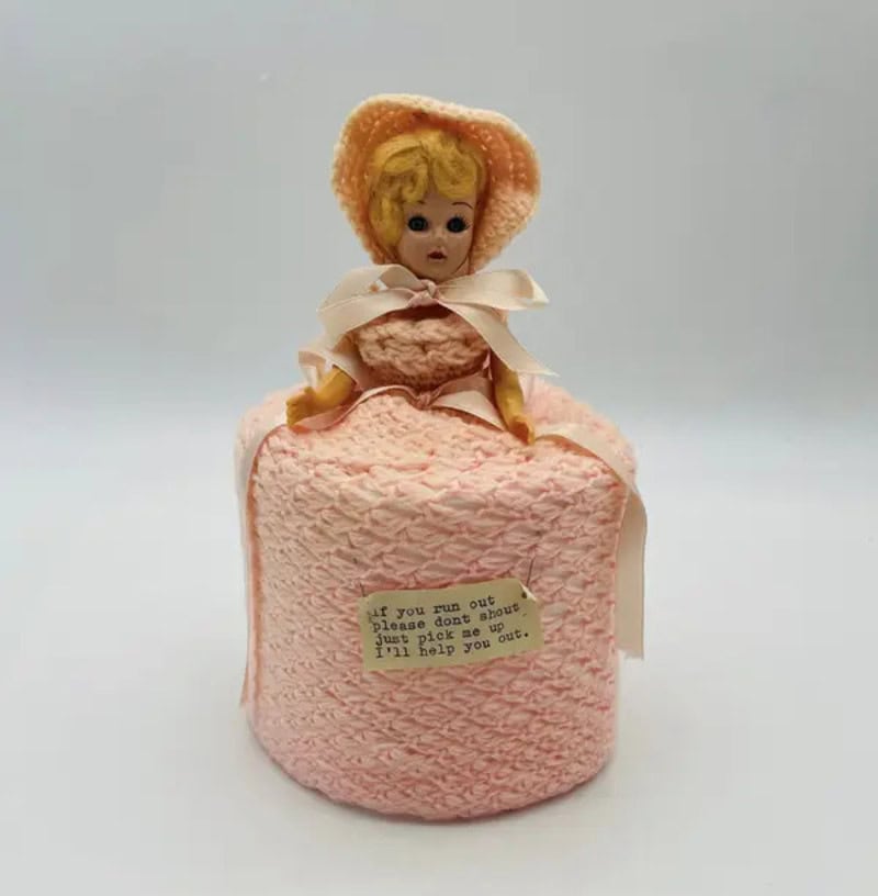 Vintage doll on pink textured cake with note, nostalgic household item.