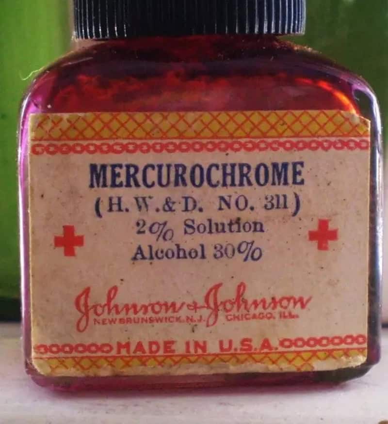 Vintage Mercurochrome bottle with label, red cross symbols, and old-fashioned design.