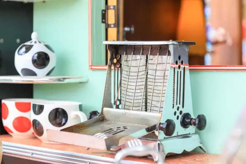 Vintage electric sandwich toaster on a kitchen counter with colorful background.