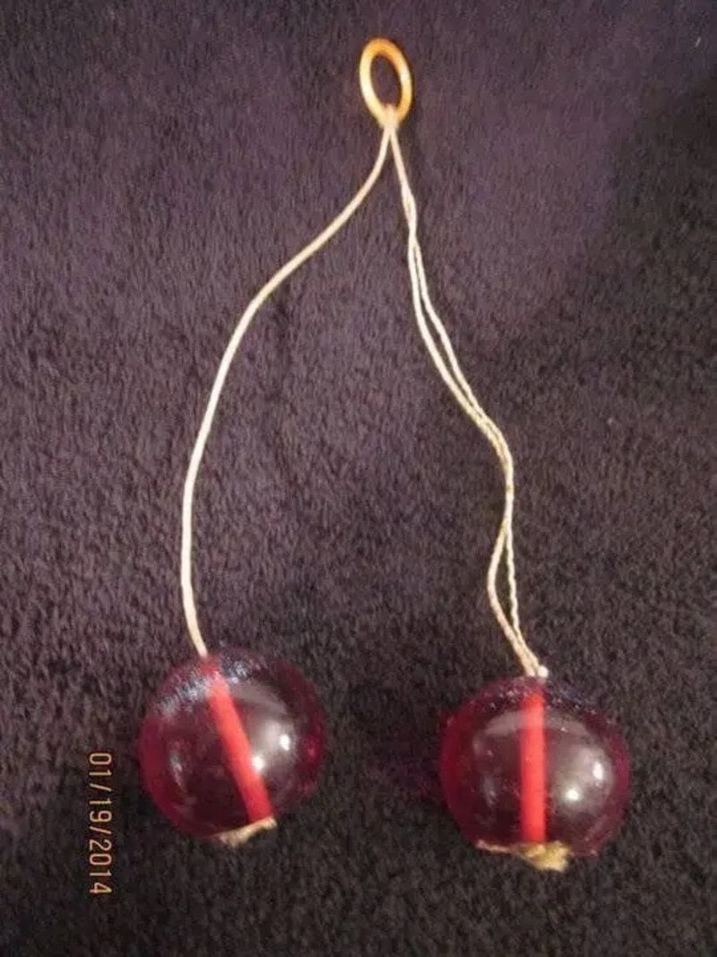 Vintage red marbles with a string and a loop for holding.