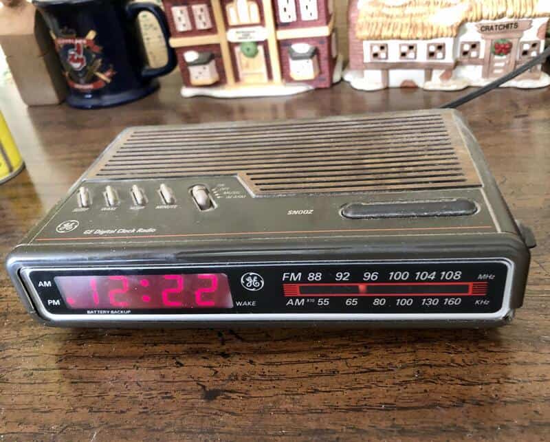 Vintage GE alarm clock with radio and digital display on wooden surface.