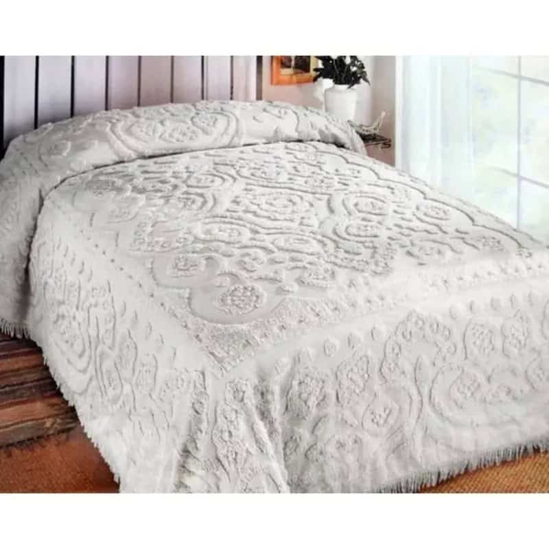 Vintage white embroidered bedspread on a bed in a cozy room.