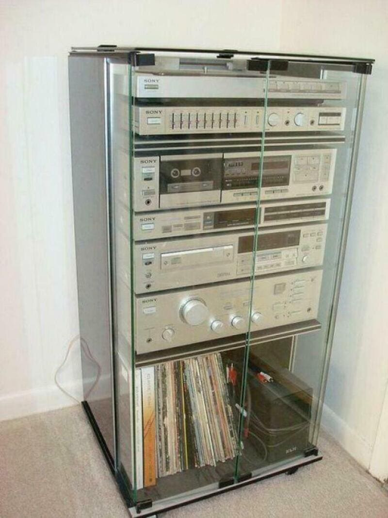 Vintage stereo system with multiple components in a glass cabinet.