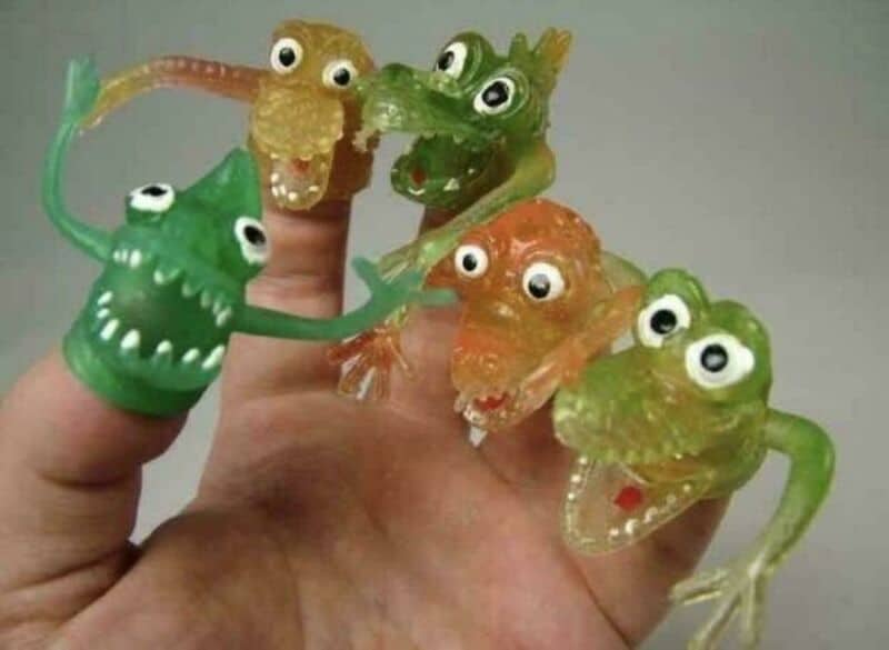 Colorful gummy worms with googly eyes on fingers, resembling monsters.