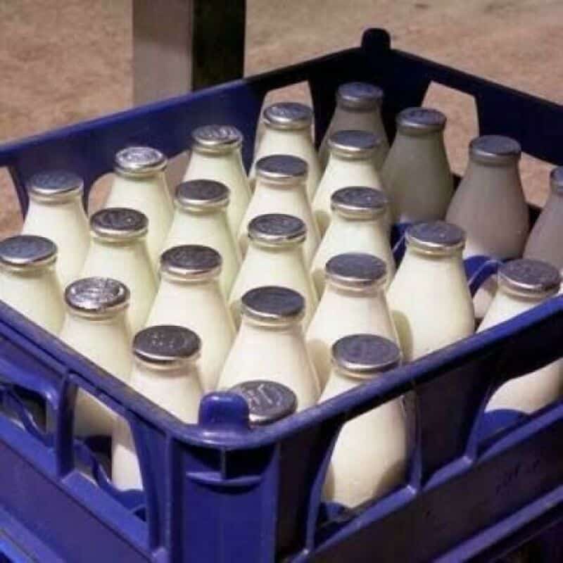 Glass bottles of milk in a blue crate, vintage style, 80s nostalgia.